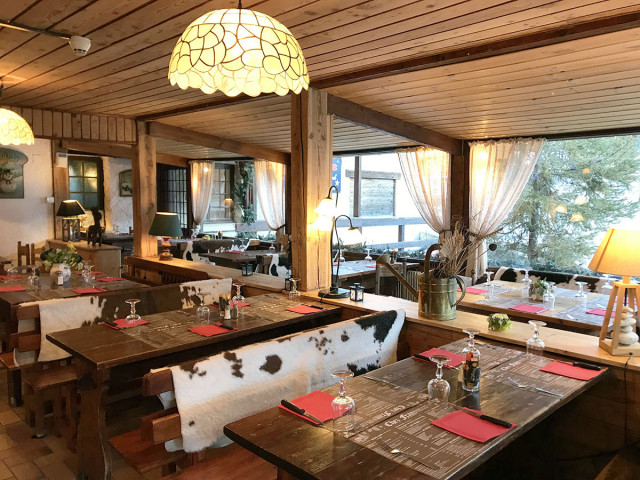 The restaurant's interior, featuring tables and chairs, a chalet atmosphere, and mountain decor.