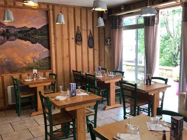 Bright restaurant dining room with wooden interior decor, matching tables and chairs, painting on the wall, French doors opening onto the shopping arcade