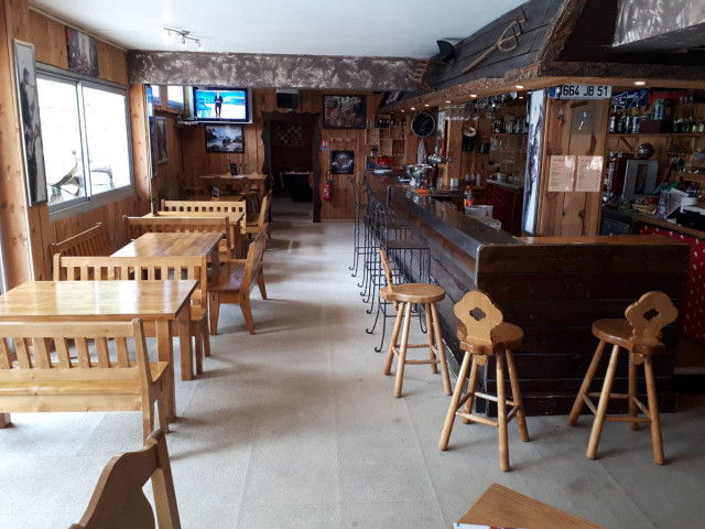 Salle d'accueil du restaurant, comptoir bar en bois laqué, tables et chaises, tabourets, salle de jeux au fond, TV, fenêtres donnant sur l'extérieur - © E Fenech Salle d'accueil du restaurant, comptoir bar en bois laqué, tables et chaises, tabourets, salle de jeux au fond, TV, fenêtres donnant sur l'extérieur
