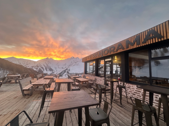 Wooden terrace of the altitude restaurant Le Panorama, sunset and view of the slopes