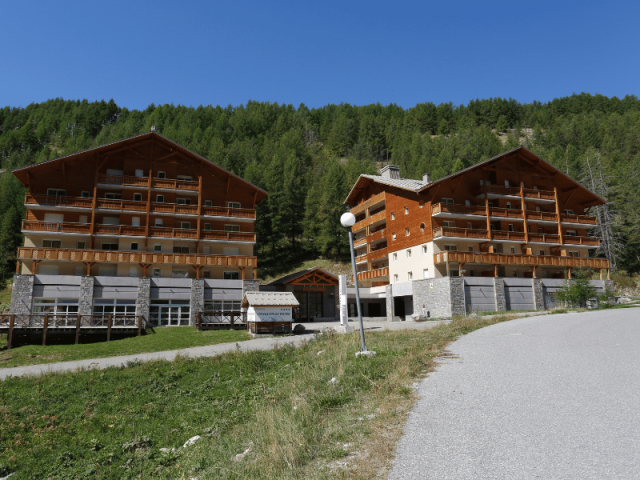 Vue de la résidence, deux bâtiments sur plusieurs étages reliés par une aile centrale avec réception, cadre montagne Vue de la résidence, deux bâtiments sur plusieurs étages reliés par une aile centrale avec réception, cadre montagne