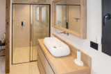 Vue de salle de bains avec évier, grand bac à douche, ameublement bois
