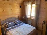 Bright bedroom with wooden furniture, panelling, double bed, window and curtains