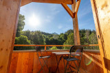 Sunny terrace with table and chairs, unobstructed view of a mountain forest