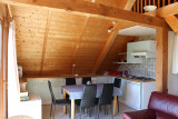 Bright living room in the attic with dining table, kitchen, sofa, French doors, wooden furniture