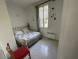 Bright bedroom with double bed, tiled floor, wooden furniture