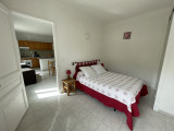 Bright bedroom with double bed, tiled floor, wooden furniture, door to living room