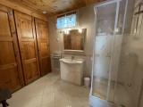 Bright tiled bathroom with shower tray, wooden furniture, window