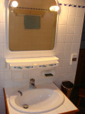 Coin de salle de bains avec évier, miroir, mur et sol carrelés
