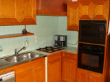 Kitchen area with wooden furniture, gas hobs, oven, microwave, tiled walls