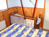 Bright children's bedroom with wooden furniture and wooden panelling, view of a single bed and cot
