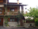 View of a three-storey house made of wood and stone, metal balconies, garden shed, courtyard