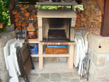 Garden shed made out of wood, wood pile, exterior stone chimney used for barbecue, folding chairs