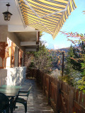 Exterior terrace of a house made out of stone, wooden fence, outdoor table, autumn scenery