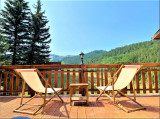 Terrasse en bois du chalet avec transat, vue dégagée avec paysage d'été