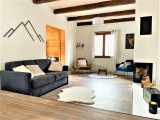 Grand séjour lumineux avec cheminée, canapé, fauteuils, ameublement bois, poutres apparentes, parquet au sol, fenêtre