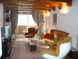 Bright living room with sofa, armchairs, TV, rug, French window