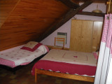 Chambre à coucher sous combles avec lit double, lit simple, ameublement bois, sol carrelé