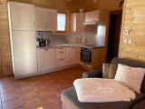 Bright and modern kitchen area, wooden furniture, panelling, armchair, window and curtains
