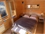 Bright bedroom with wooden furniture, panelling, double bed with mirror, curtains, unobstructed view of the mountains from window