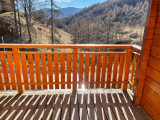 Wooden sunlit terrace with fence, unobstructed view of an autumn forest