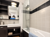 Salle de bain avec baignoire et paroi de douche en verre, meuble en bois foncé