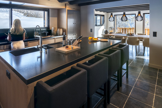 Séjour moderne et lumineux, coin cuisine, grande table à manger et fauteuils confortables, porte-fenêtres et fenêtres