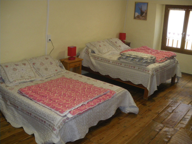 Chambre à coucher lumineuse avec deux lits doubles, ameublement bois, parquet au sol, fenêtre Chambre à coucher lumineuse avec deux lits doubles, ameublement bois, parquet au sol, fenêtre