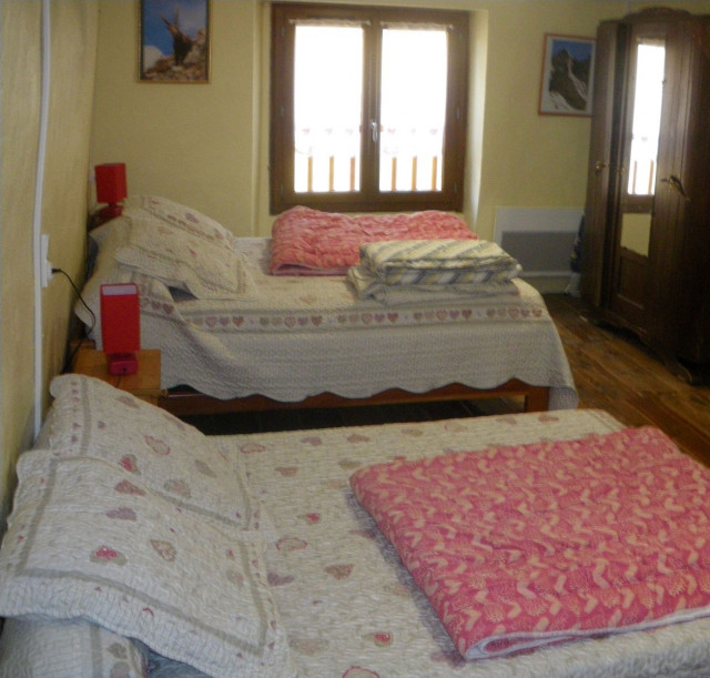 Chambre à coucher lumineuse avec deux lits doubles, ameublement bois, parquet au sol, fenêtre Chambre à coucher lumineuse avec deux lits doubles, ameublement bois, parquet au sol, fenêtre