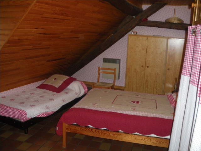 Chambre à coucher sous combles avec lit double, lit simple, ameublement bois, sol carrelé Chambre à coucher sous combles avec lit double, lit simple, ameublement bois, sol carrelé