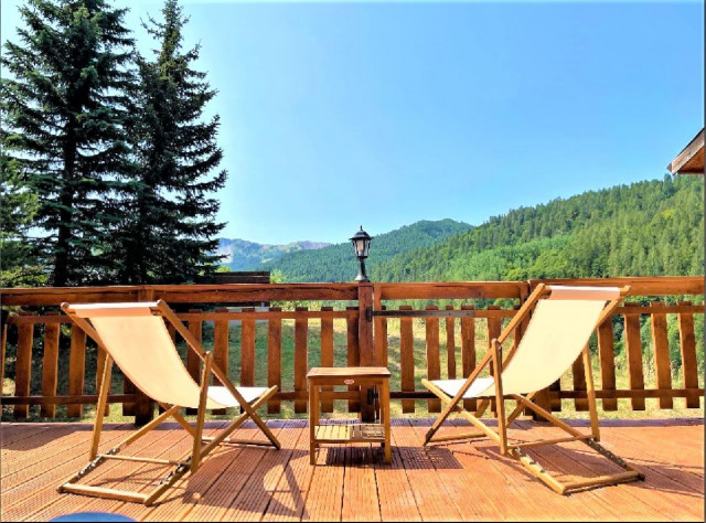 Terrasse en bois du chalet avec transat, vue dégagée avec paysage d'été Terrasse en bois du chalet avec transat, vue dégagée avec paysage d'été