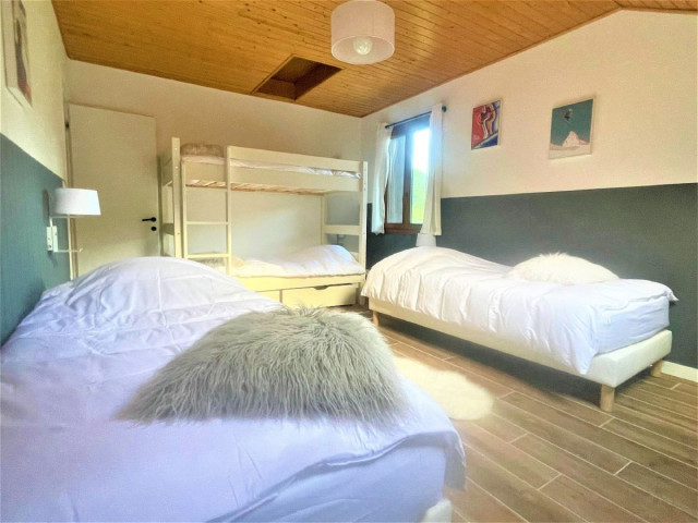 Chambre à coucher lumineuse avec lits superposés et deux lits simples, ameublement bois, parquet au sol, fenêtre Chambre à coucher lumineuse avec lits superposés et deux lits simples, ameublement bois, parquet au sol, fenêtre