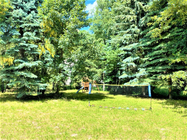 Jardin ensoleillé avec aire de jeux et filet de volley-ball Jardin ensoleillé avec aire de jeux et filet de volley-ball