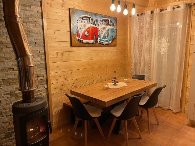 Living room with wooden furniture, dining table, wood stove, window and curtains, tiled floor