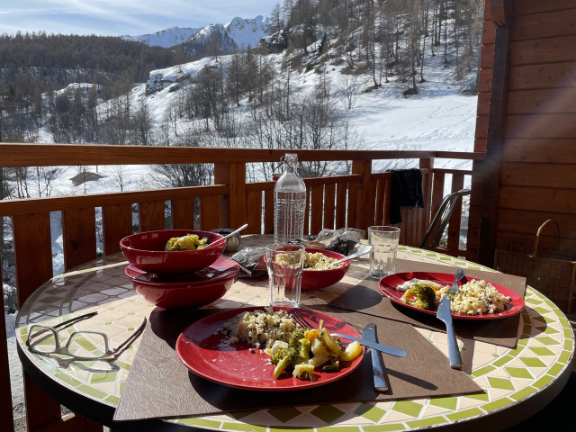 Wooden terrace with fence, round dining table, unobstructed view of snow-capped mountains
