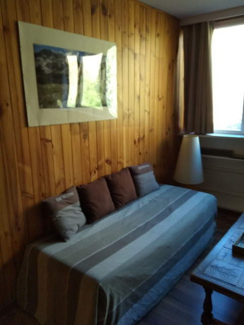 Bright living room with wooden furniture, panelling, sofa, window and curtains
