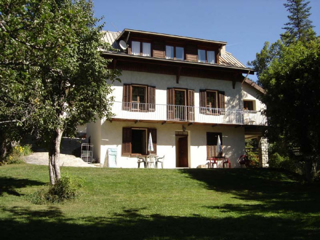 Vue de la maison avec appartement en rez-de-jardin, terrasse, jardin, table de jardin, végétation