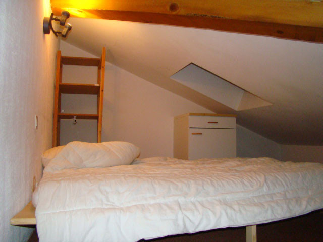 Chambre à coucher sous combles avec lit double, ameublement bois, espace de rangement