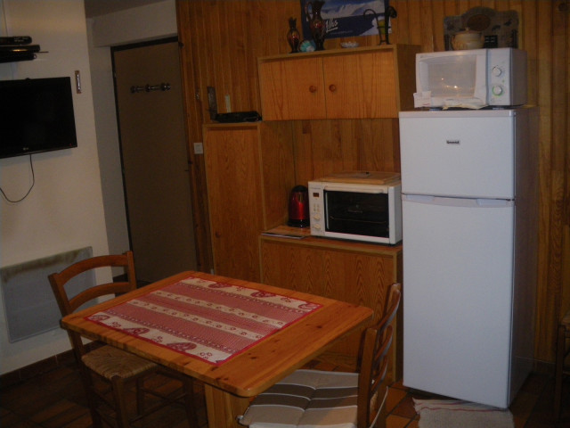 Coin séjour et cuisine avec table à manger, four à micro-ondes, TV, ameublement bois et parquet au sol - © J Matheron Coin séjour et cuisine avec table à manger, four à micro-ondes, TV, ameublement bois et parquet au sol