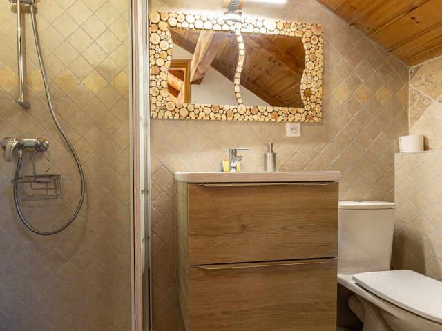 Bright tiled bathroom, shower tray, sink, wooden furnishings
