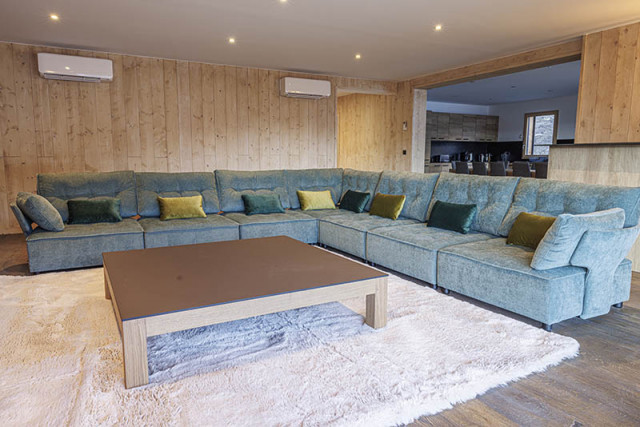 Large, comfortable and bright chalet living room, large corner sofa, rug, coffee table, wooden furniture, kitchen area