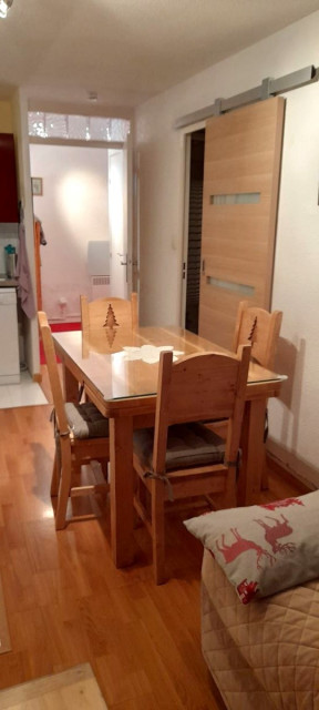 Séjour lumineux avec canapé, table à manger, coin cuisine, ameublement bois, parquet au sol