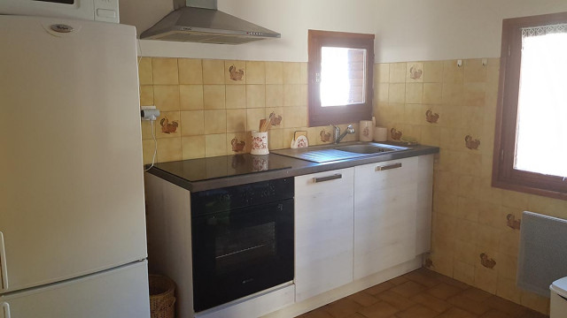 Coin cuisine carrelée avec plaques électriques, évier, fenêtres