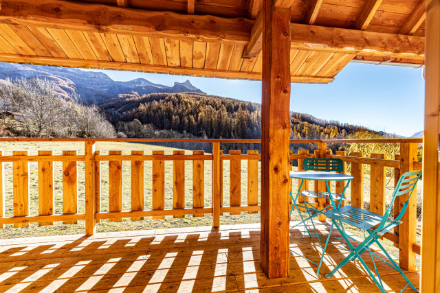 Large wooden terrace with garden table overlooking a mountain forest landscape