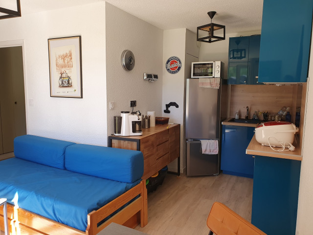 Living area with sofa bed and coffee table, fully equipped kitchen area