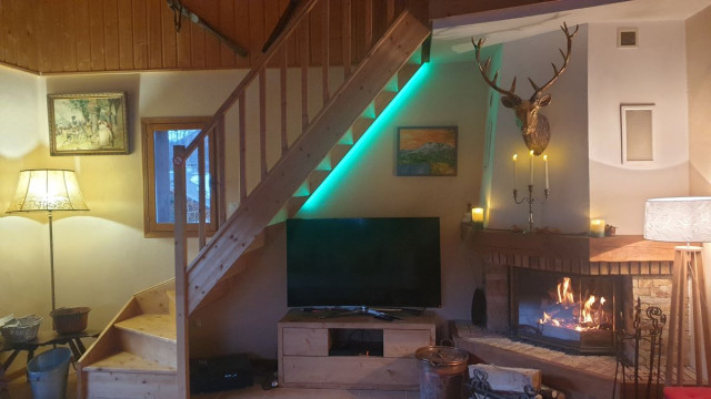 Apartment living room with fireplace, TV, window, wooden furniture, staircase to the upper floor