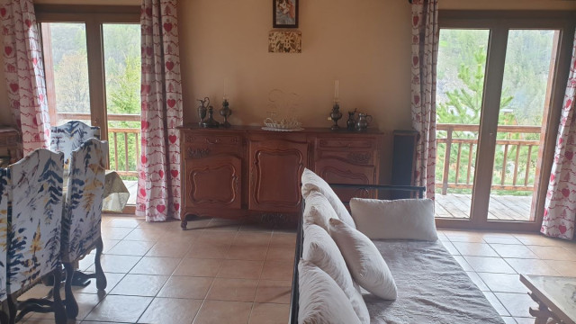 Bright living room with wooden furniture, sofa, French doors, tiled floor