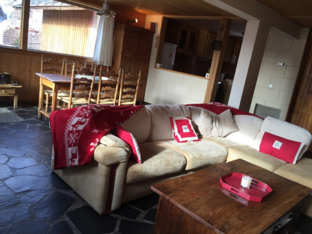 Salon lumineux de chalet tout confort avec canapé, table basse, table à manger, fenêtre