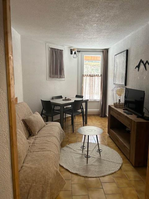 Séjour d'appartement avec canapé, TV, table à manger, ameublement bois, fenêtre