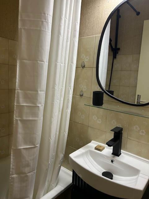 Bathroom with bathtub, sink and mirror, tiled floor - © V Van Rompu Bathroom with bathtub, sink and mirror, tiled floor